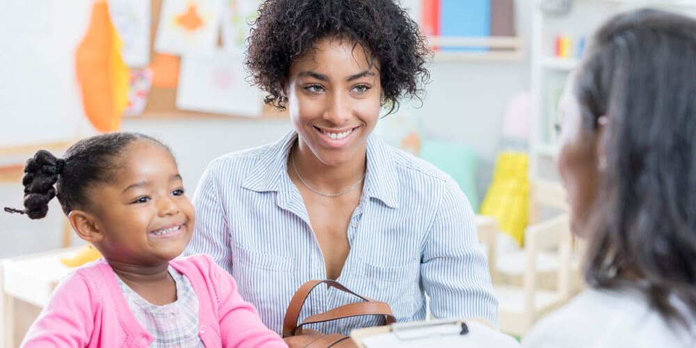 Parent-teacher-image A teacher hosts a parent teacher conference with a smiling mom and her child