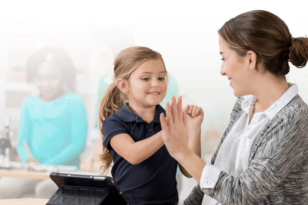 Direct-Instruction-Banner-Image-mobile Elementary teacher high-fiving a student while working on a tablet