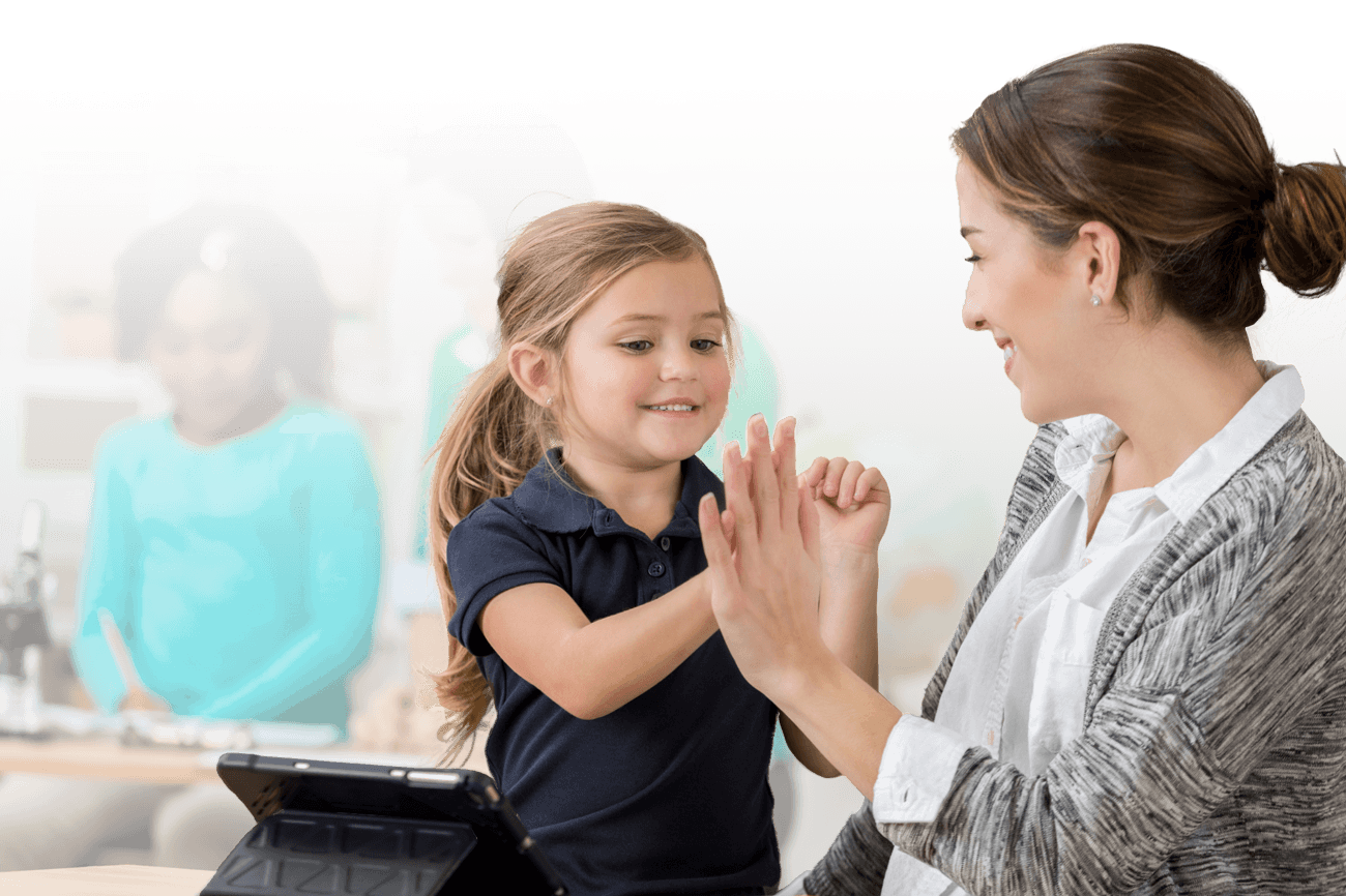 Direct-Instruction-Banner-Image-tablet Elementary teacher high-fiving a student while working on a tablet